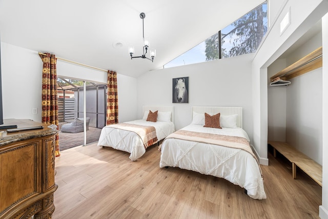 bedroom featuring access to outside, high vaulted ceiling, a notable chandelier, and light hardwood / wood-style floors