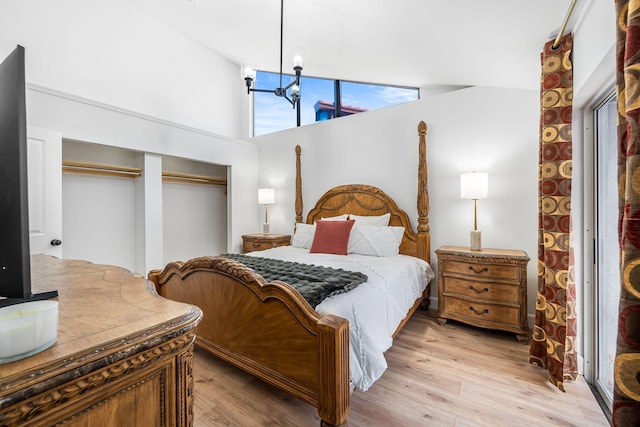 bedroom with an inviting chandelier, lofted ceiling, light hardwood / wood-style flooring, and a closet