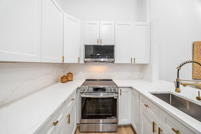 kitchen featuring light stone countertops, white cabinetry, sink, and stainless steel appliances