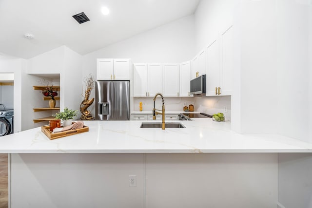 kitchen with lofted ceiling, light stone countertops, white cabinetry, kitchen peninsula, and stainless steel appliances