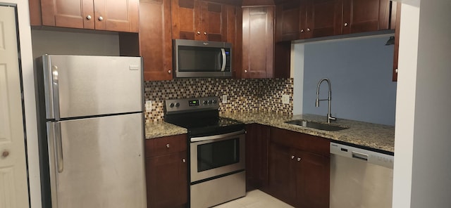 kitchen with decorative backsplash, appliances with stainless steel finishes, light stone counters, and sink