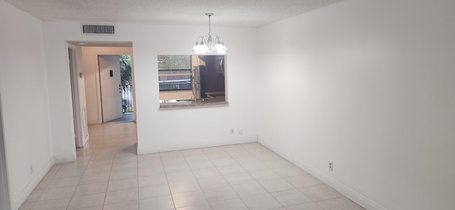 empty room featuring a textured ceiling and a notable chandelier