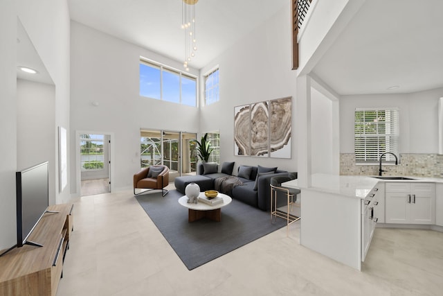 living room featuring rail lighting, a towering ceiling, sink, and a wealth of natural light