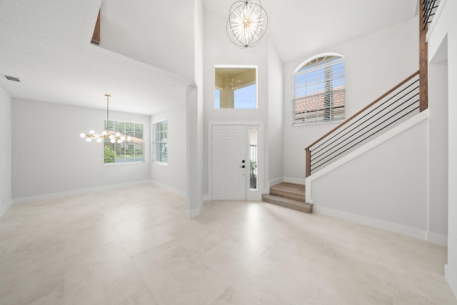 foyer with a notable chandelier, a textured ceiling, and a high ceiling