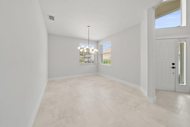 interior space with a textured ceiling, plenty of natural light, and a notable chandelier