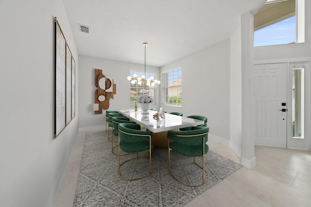 dining room with a textured ceiling, a wealth of natural light, and a notable chandelier