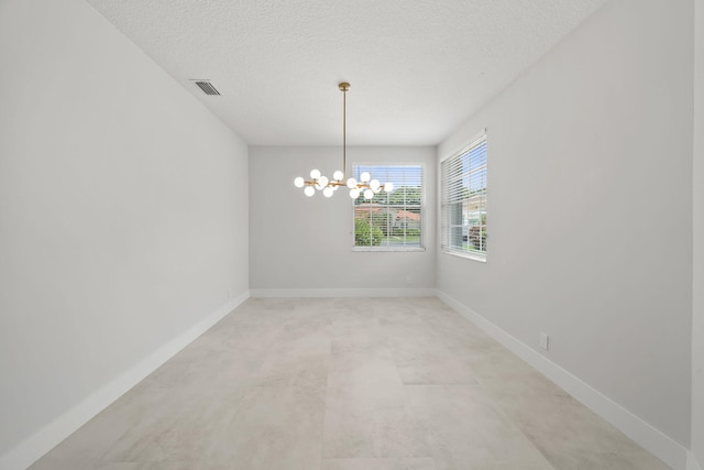 empty room featuring a chandelier and a textured ceiling