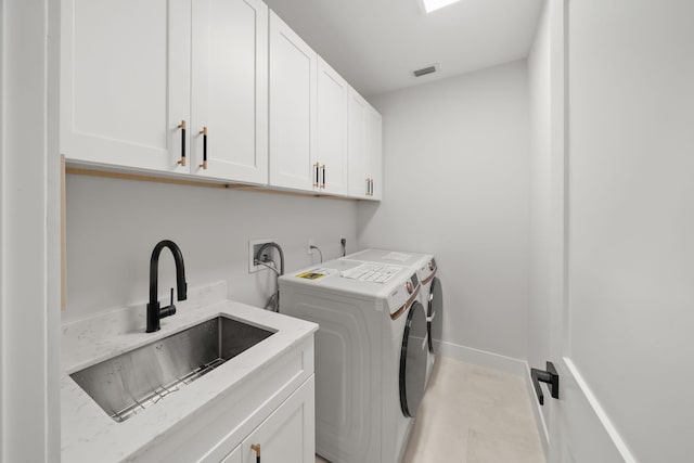 washroom with cabinets, washing machine and clothes dryer, and sink