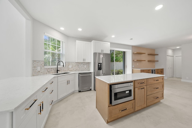 kitchen featuring sink, white cabinets, stainless steel appliances, and a kitchen island