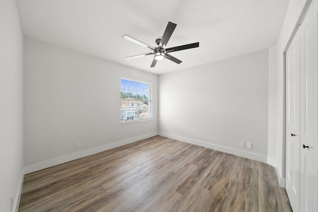 unfurnished bedroom with a closet, ceiling fan, hardwood / wood-style floors, and a textured ceiling