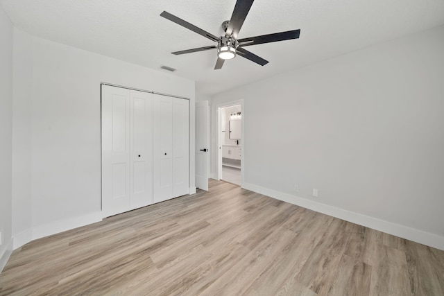 unfurnished bedroom featuring a textured ceiling, a closet, light hardwood / wood-style flooring, and ceiling fan