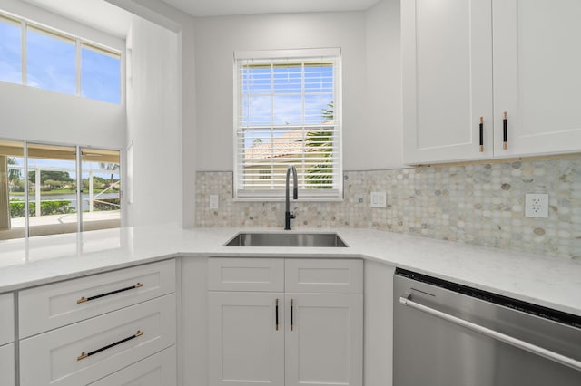 kitchen with white cabinets, stainless steel dishwasher, light stone countertops, and sink