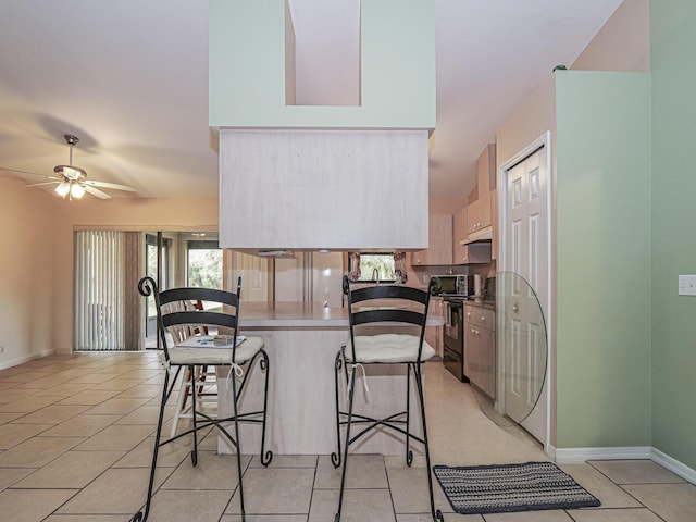 kitchen featuring ceiling fan, black electric range oven, a kitchen bar, and light tile patterned flooring