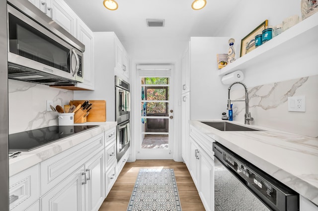 kitchen featuring light stone counters, sink, black appliances, light hardwood / wood-style flooring, and white cabinetry