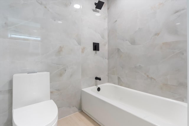 bathroom with toilet, tile walls, and tiled shower / bath