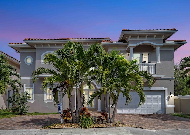 mediterranean / spanish-style home featuring a garage and a balcony