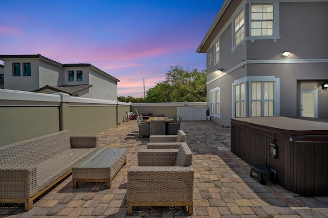 patio terrace at dusk featuring an outdoor living space and a hot tub