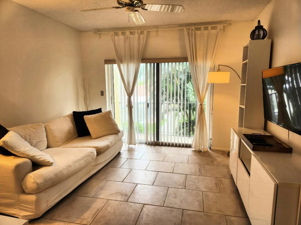 living room with ceiling fan and a textured ceiling