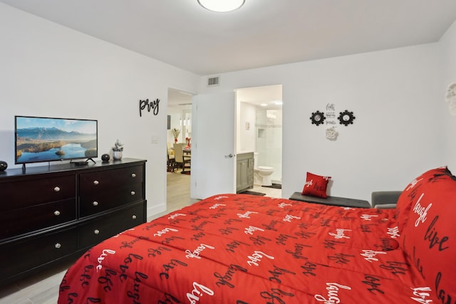 bedroom with ensuite bathroom and light hardwood / wood-style floors