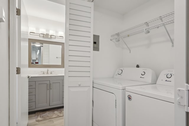 laundry area with independent washer and dryer, light hardwood / wood-style flooring, and sink