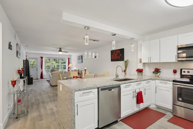 kitchen featuring white cabinets, stainless steel appliances, kitchen peninsula, and sink