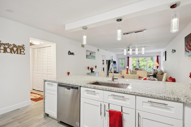 kitchen featuring stainless steel dishwasher, sink, decorative light fixtures, light hardwood / wood-style floors, and white cabinetry