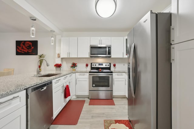 kitchen featuring sink, light hardwood / wood-style flooring, white cabinetry, kitchen peninsula, and stainless steel appliances