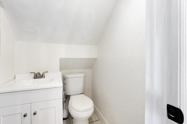 bathroom with tile patterned floors, vanity, toilet, and lofted ceiling