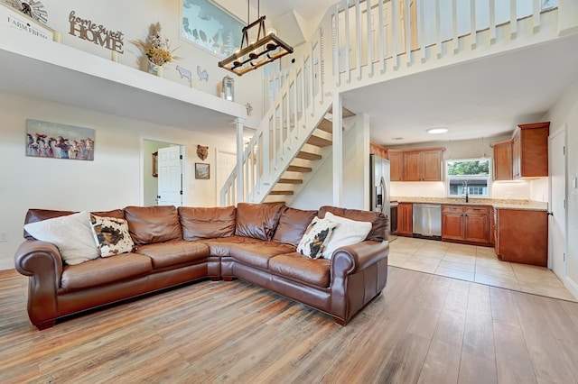 living room with sink, a high ceiling, and light wood-type flooring