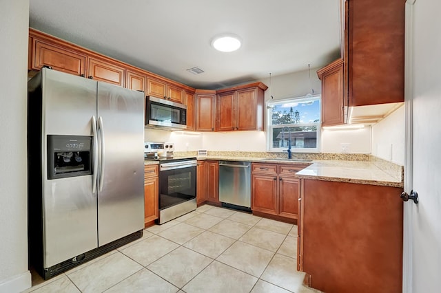 kitchen featuring light stone countertops, sink, light tile patterned floors, and stainless steel appliances