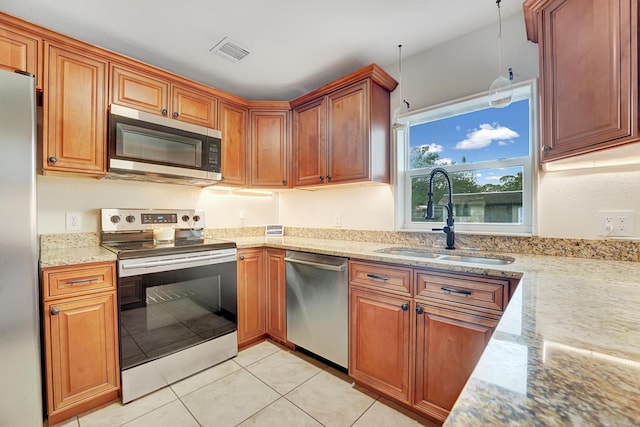 kitchen with light stone counters, sink, light tile patterned floors, and stainless steel appliances