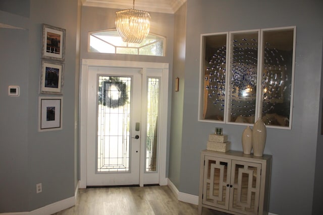 entryway featuring light hardwood / wood-style flooring, ornamental molding, and a notable chandelier