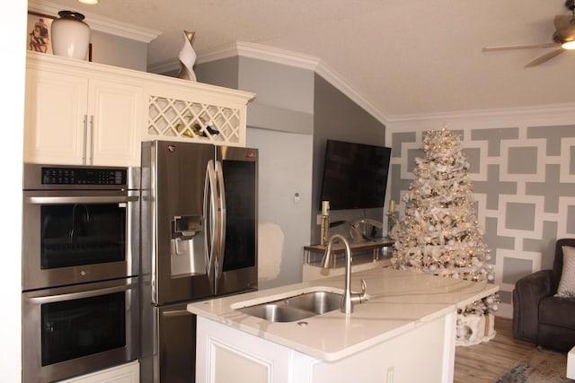 kitchen with appliances with stainless steel finishes, ceiling fan, sink, light hardwood / wood-style floors, and white cabinetry