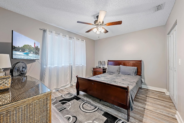 bedroom with ceiling fan, a closet, a textured ceiling, and hardwood / wood-style flooring