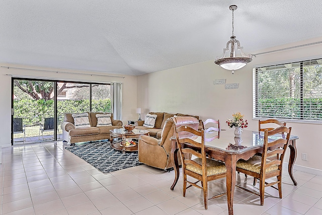 dining room featuring a textured ceiling, light tile patterned flooring, and vaulted ceiling