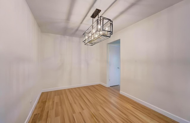 unfurnished dining area featuring a chandelier and wood-type flooring