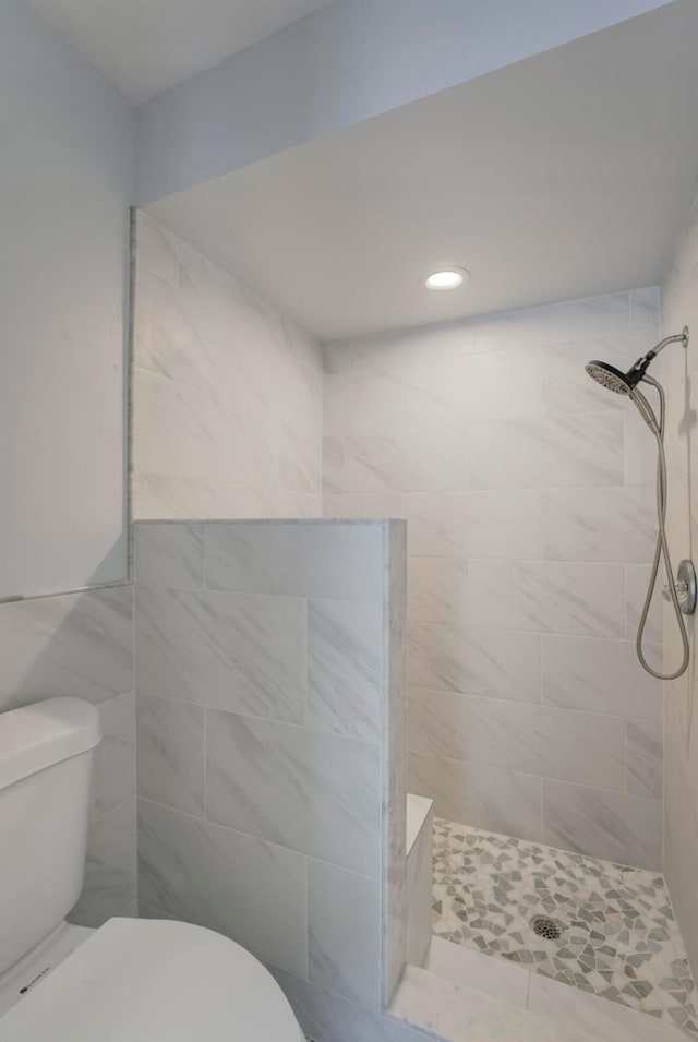 bathroom with tiled shower and toilet