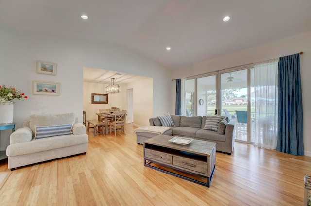 living room with light wood-type flooring, vaulted ceiling, and an inviting chandelier