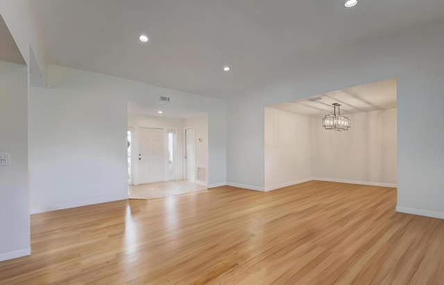 unfurnished room with a chandelier and light wood-type flooring