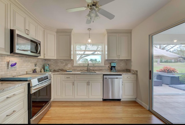 kitchen featuring light hardwood / wood-style floors, ceiling fan, stainless steel appliances, pendant lighting, and sink