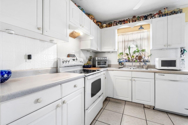 kitchen featuring white appliances, sink, backsplash, light tile patterned flooring, and white cabinets