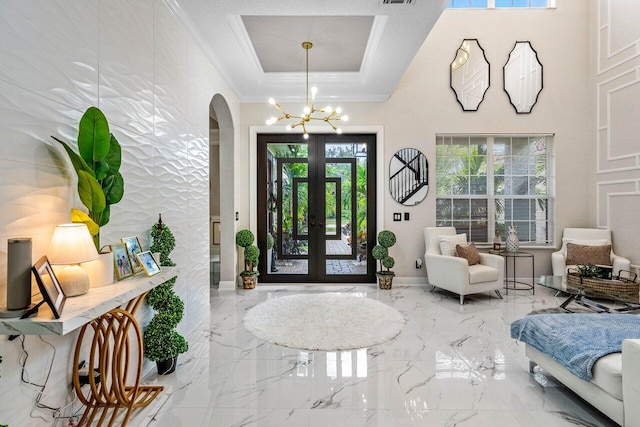 foyer entrance featuring crown molding, french doors, and an inviting chandelier