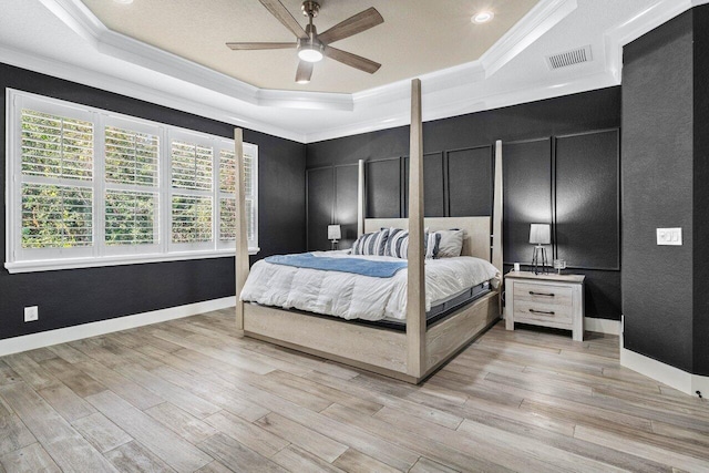 bedroom featuring a tray ceiling, visible vents, multiple windows, and ornamental molding