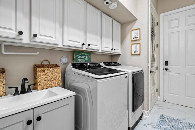 washroom with marble finish floor, a sink, washing machine and dryer, cabinet space, and baseboards