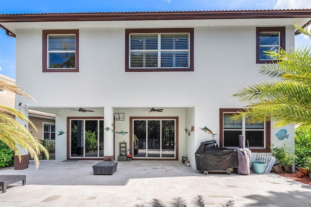 rear view of house with stucco siding, a patio, and ceiling fan