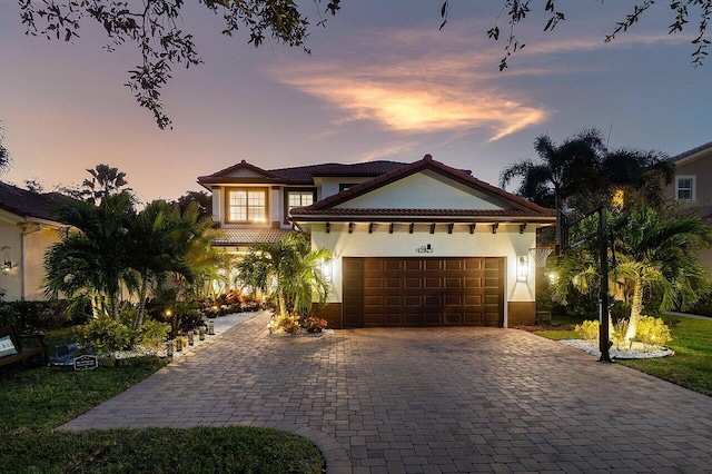 mediterranean / spanish house with decorative driveway, an attached garage, and stucco siding