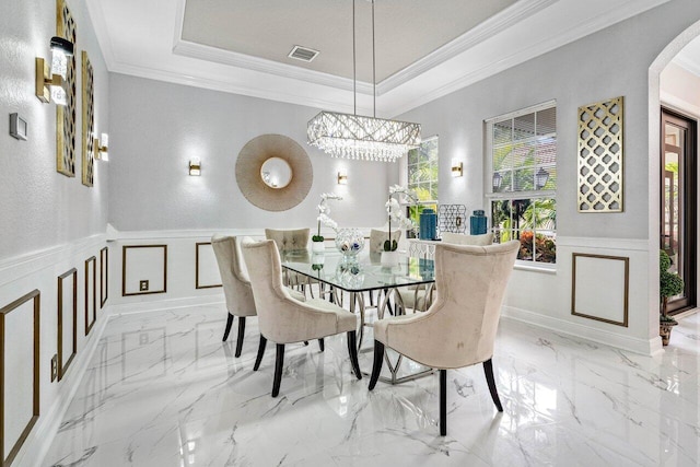 dining room with visible vents, ornamental molding, wainscoting, arched walkways, and a decorative wall