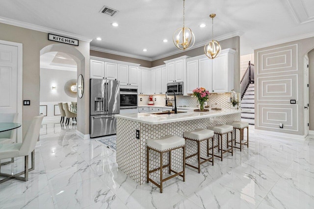 kitchen featuring a kitchen bar, marble finish floor, arched walkways, appliances with stainless steel finishes, and a peninsula