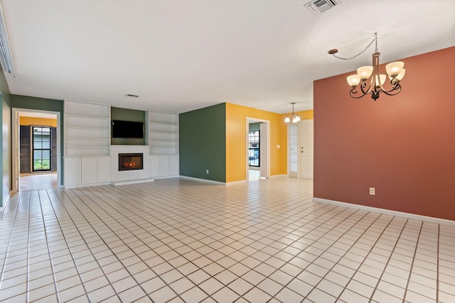 unfurnished living room featuring a notable chandelier, light tile patterned floors, and built in shelves