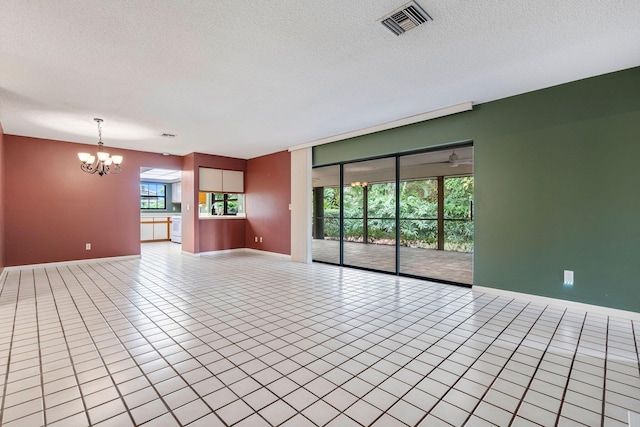 unfurnished living room featuring a notable chandelier, a textured ceiling, and light tile patterned flooring